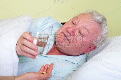 生病的老人躺在床上，正在吃药