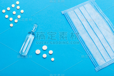 医学模拟与药物，以保护健康和治疗的病毒，一个口罩和药丸与疫苗在蓝色背景与复制空间的近距离。
