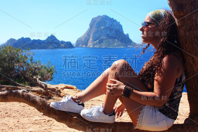 一个黑发白种女孩的暑假坐在树枝上欣赏埃斯韦德拉岛在卡拉霍特在伊比沙岛