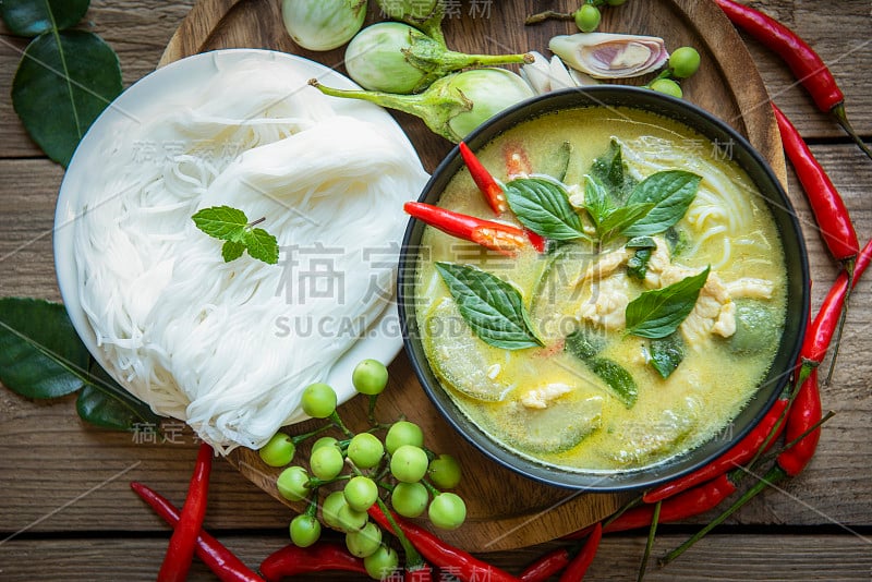 鸡肉绿色咖喱泰国食物汤碗与米粉配料蔬菜香草和辣椒辣椒木背景，传统的绿色咖喱鸡肉菜肴亚洲食物。俯视图