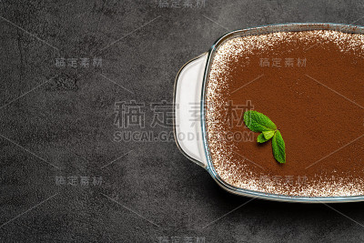 传统的意大利提拉米苏甜点在玻璃烤盘在混凝土背景
