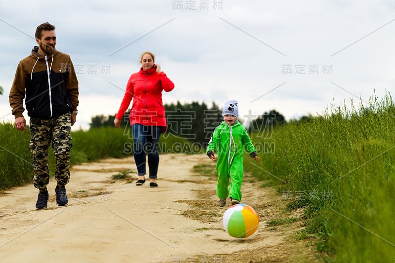 一个年轻的家庭带着一个孩子在田野里散步