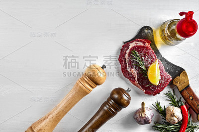 新鲜的生牛排，配上香草，大蒜，橄榄油，胡椒，盐，迷迭香和一把厨房斧头。俯视图