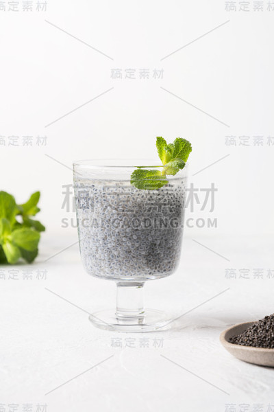 健康的排毒饮料与罗勒种子在玻璃上的白色背景。垂直格式。