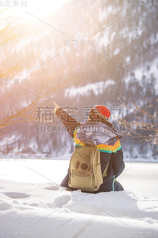 户外探险:一个白人女孩坐在雪地里欣赏风景。美丽的冬季风景，奥地利