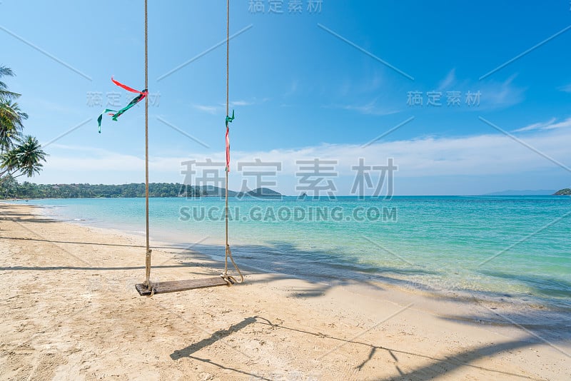 在泰国普吉岛的夏季海滩上，秋千悬挂在椰子树上。夏季，旅游，假期和假日概念