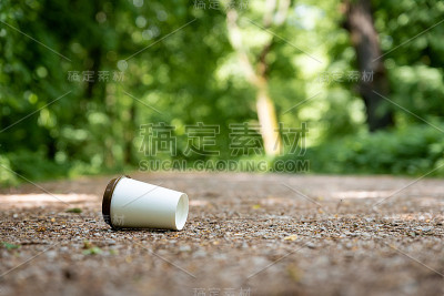 一次性咖啡杯被扔在森林里的地上