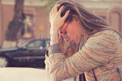 侧影强调悲伤的年轻女子坐在户外