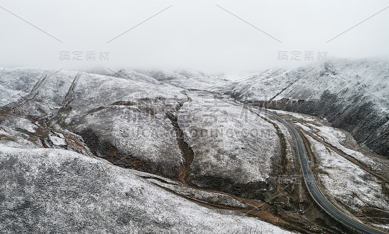 蜿蜒穿过被雪山环绕的山谷的乡村道路