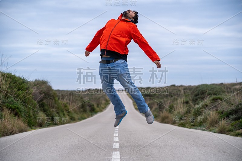 一个年轻人在一条柏油路的中间跳