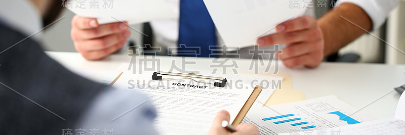 男性手臂握住合同形式夹在垫子上