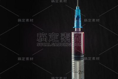 黑色背景下的红色药物注射器。特写镜头。本空间