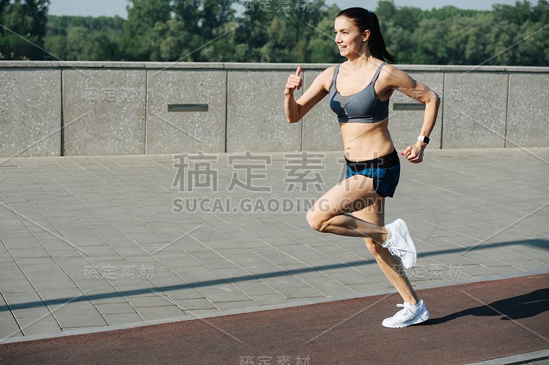 兴奋的女人在室外人行道旁边的跑道上快速奔跑