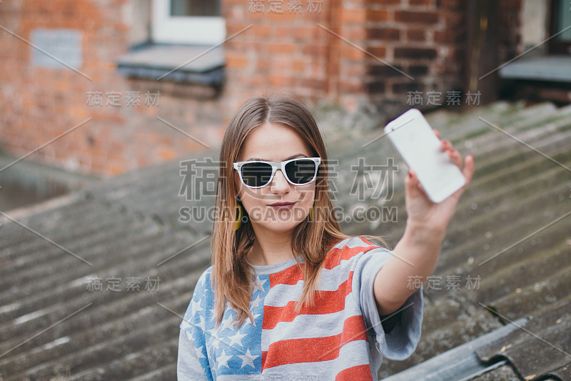 一个最时髦的女孩在一个老院子里拿着手机自拍