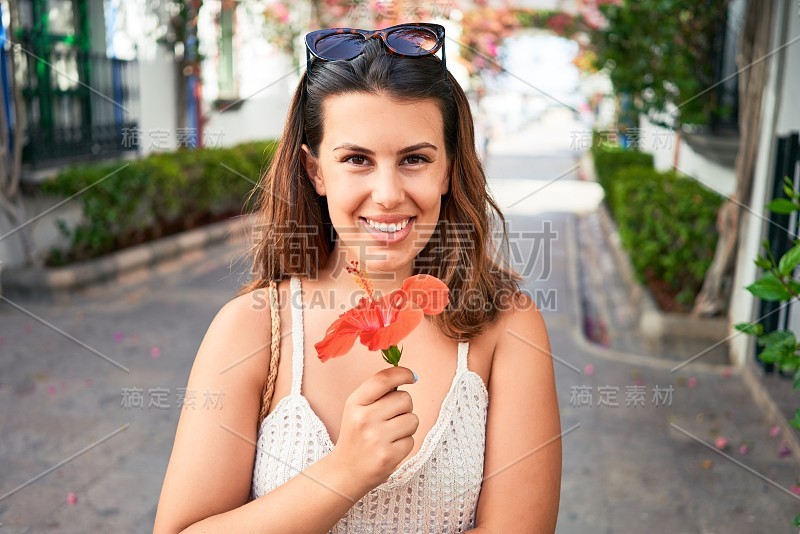 美丽的年轻女子在莫根港的五彩缤纷的村庄里，在暑假的街道上闻着花香，快乐地微笑着