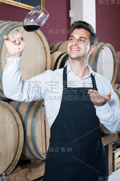 男售货员拿着酒杯在酒窖里卖酒