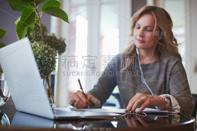 女人在她的明亮舒适和美丽的家庭办公室工作与笔记本电脑。