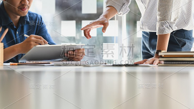 一位商人在和同事开会时在平板电脑上写字。