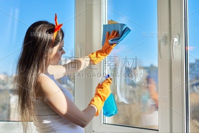 打扫房子，戴手套的女人用洗涤剂和抹布擦窗户