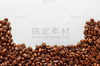 咖啡豆被一个近距离散落在白色的桌子上，俯视图中，有一个放置文字的地方