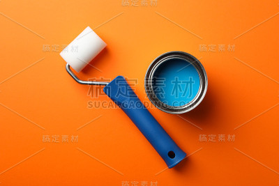 橘色背景上的蓝色油漆和滚轮，俯视图