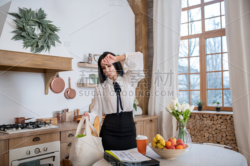 年轻女子下班后拿着购物袋，感觉很累