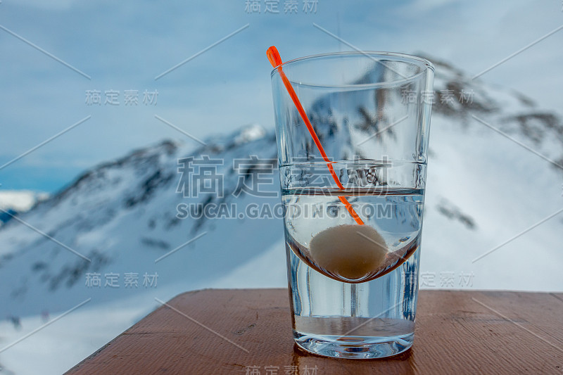 桌子上放着一杯酒，背景是白雪覆盖的山脉