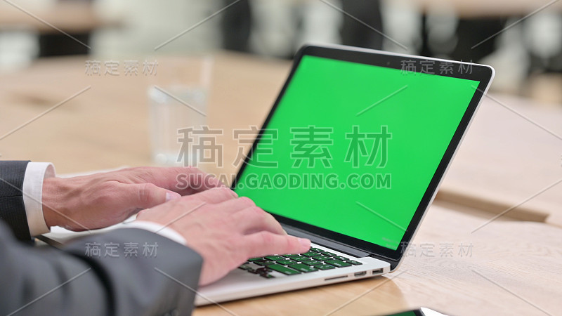 商人用绿色屏幕在笔记本电脑上打字
