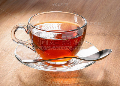 玻璃杯茶与茶碟和茶匙特写在草巾纸的背景