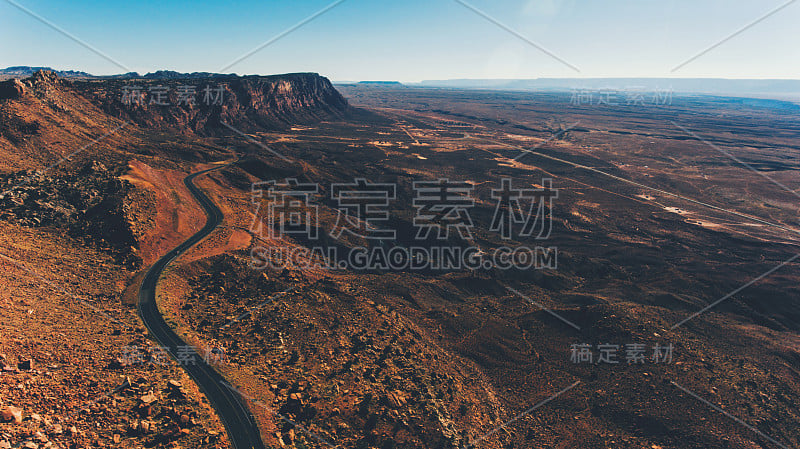 鸟瞰图美丽的岩石山脉与沥青公路沿着。鸟瞰美国沙漠景观地区的赤壁