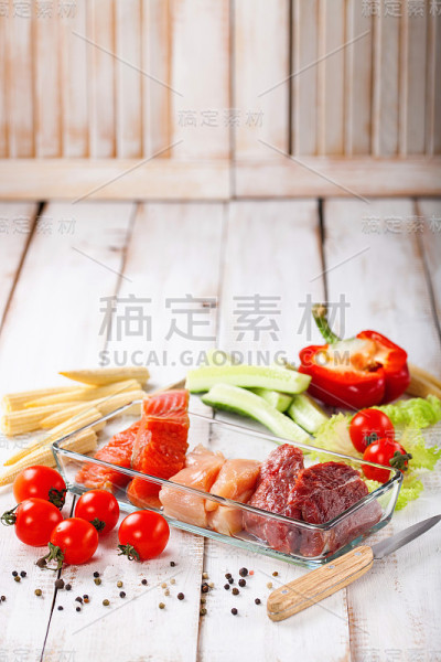 饮食产品-生牛肉和鸡肉，鲑鱼和蔬菜在轻木制背景。有选择性的重点。
