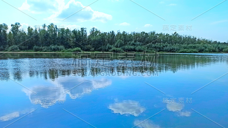 景观与河流在春天。树木倒映在河水中