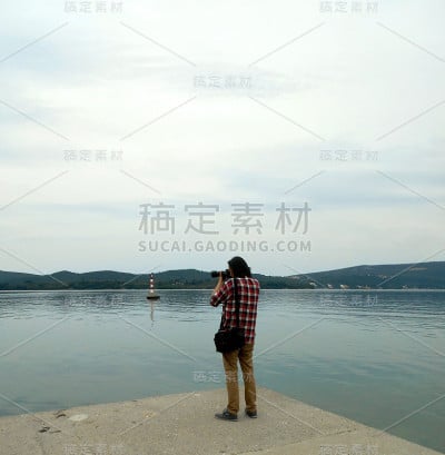 一个男人在码头上拍摄大海