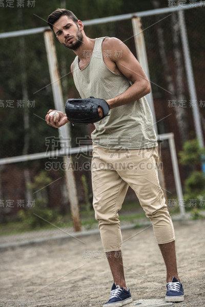年轻英俊的男子在球场上扔棒球
