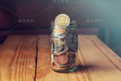 节省钱在玻璃罐上的木材背景。