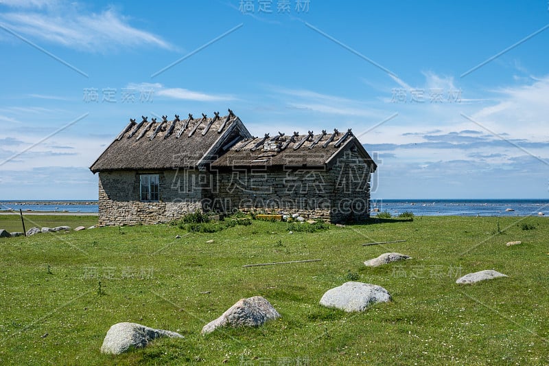 用石头建造的旧谷仓位于海边的绿地上