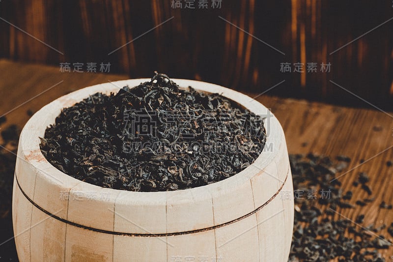 一个装满茶叶的木桶，放在烧焦的木头背景上。