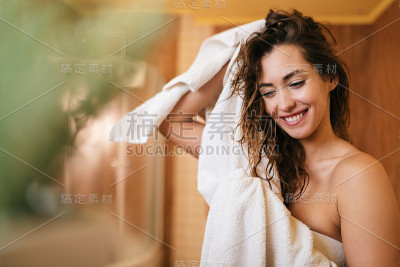 美丽幸福的女人用毛巾在浴室里擦头发。