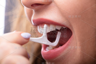 用牙线清洁牙齿的女人