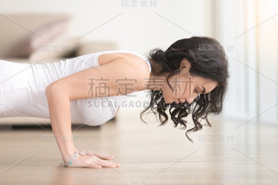 年轻迷人的女人在chaturanga dandasana姿势，客厅，特写