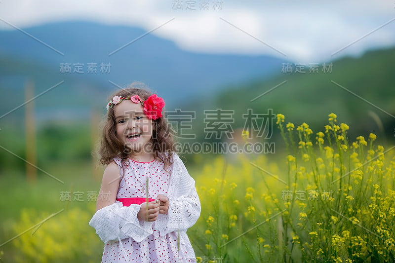 一个孩子的头发上插着一朵花，在风景如画的群山背景下玩耍