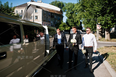 三个帅哥走进豪华轿车。婚礼当天新郎和伴郎。