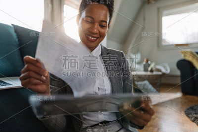 快乐的非裔美国女商人在家处理文书工作。