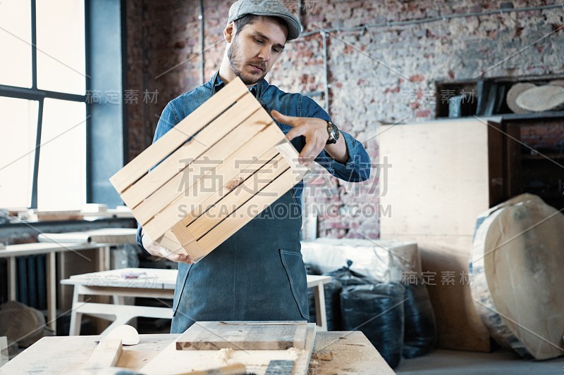 成功英俊的商人与时髦的帽子工作在木工
