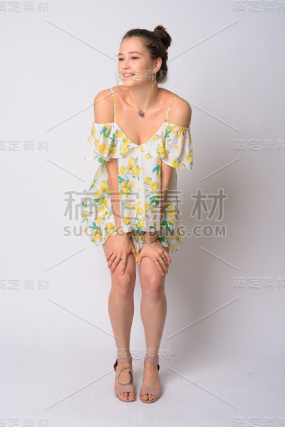 全身照片的快乐年轻美丽的女人思考与双手在膝盖上