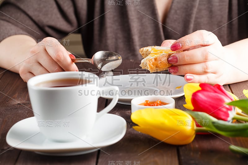 女人吃面包和果酱，喝茶