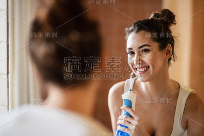 快乐的女人在浴室用牙线清洁牙齿。