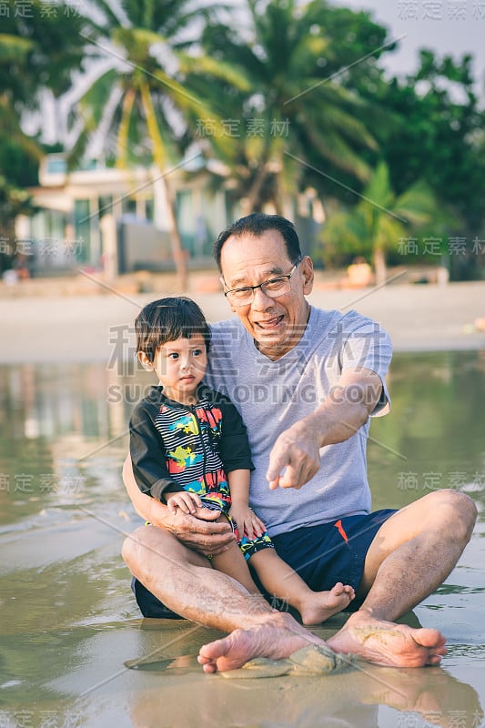 一家人在海滩上玩耍。夏天，父母和孩子们在海滩上放松。幸福健康的家庭，爷爷和侄子在沙滩上建造沙堡，面带