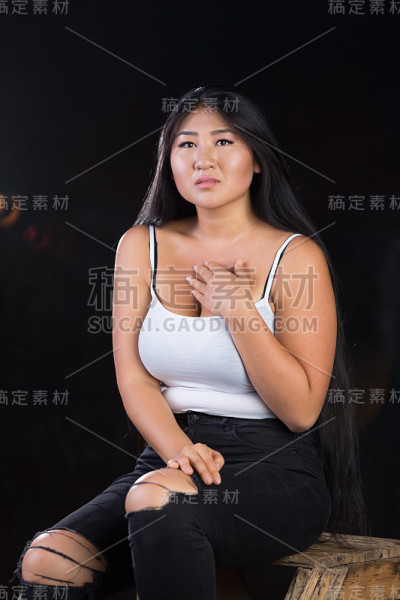 美丽的曲线模型，黑色的头发和开朗的性格在白色的t恤在黑暗的背景