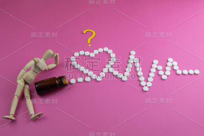 木制玩具，心形药丸，粉红色背景上的心电图。药的概念